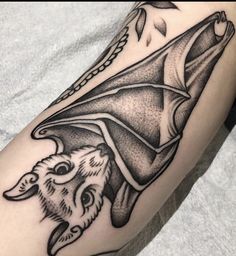 a black and white photo of a tattoo with a bat on it's arm