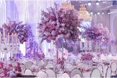 the tables are set with purple flowers and crystal chandeliers