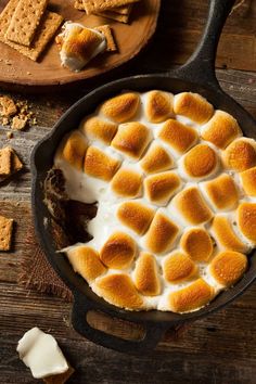 a skillet filled with marshmallows on top of a wooden table next to other items