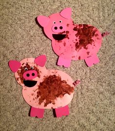 two pigs made out of construction paper on the floor with dirt all over their backs