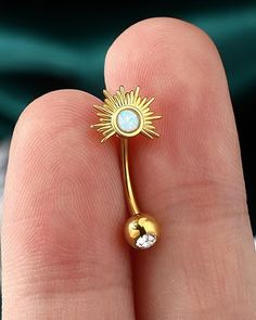 a close up of a person's hand holding a gold ring with a white stone