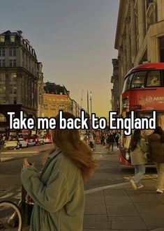 a woman walking down the street in front of a red double decker bus that says take me back to england