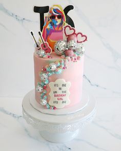 a pink birthday cake with decorations on top