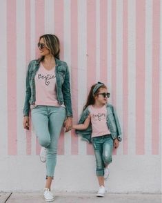 two women standing next to each other in front of a pink wall