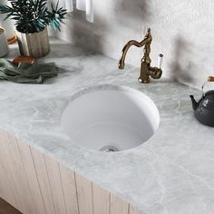 a white sink sitting on top of a counter next to a tea kettle and pot