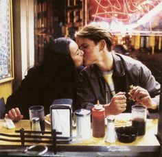 a man and woman sitting at a table sharing a kiss