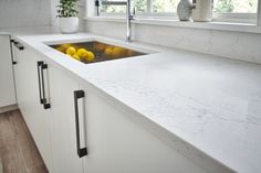 a kitchen with white counter tops and yellow lemons in the sink