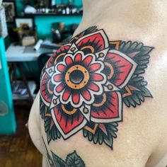 a close up of a person's shoulder with a flower tattoo on the arm