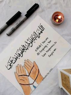 an islamic prayer with two hands and a lit candle on the table next to it