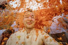 a man is covered in orange powder as he looks up at the camera with his eyes closed