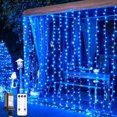 blue christmas lights are lit up in front of a gazebo and table with chairs