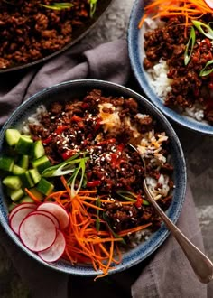 two bowls filled with meat, rice and veggies on top of a table