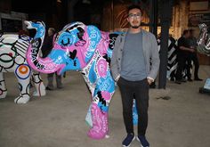 a man standing next to a colorful elephant statue