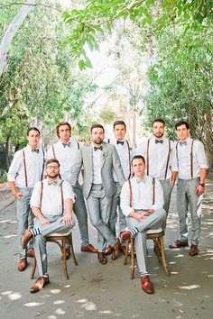 a group of men wearing suspenders and bow ties posing for a photo in front of some trees