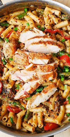 a skillet filled with chicken, pasta and vegetables