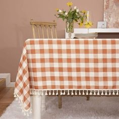 a table with a checkered cloth on it and flowers in a vase at the end