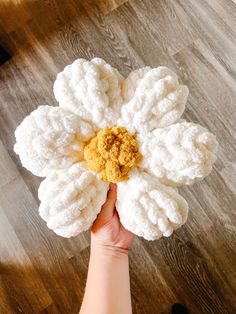 a person holding a white flower on top of a wooden floor