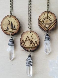 three necklaces with wood slices and glass beads hanging from chains on a white surface