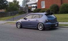 a blue car parked on the side of a road next to a red brick house