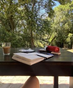 a table that has some books on it and a drink in front of the table