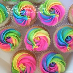 cupcakes decorated with rainbow icing in a box