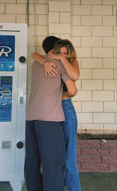 two people hugging each other in front of a machine