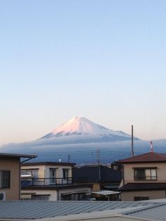 a view of a snow covered mountain in the distance from houses on rooftops and buildings