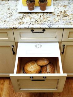 an open drawer in the middle of a kitchen with muffins and cupcakes