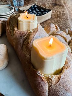 two lit candles in bread on a table