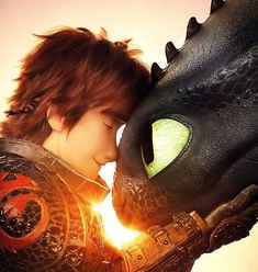 a young boy is hugging the head of a dragon in front of an orange sky