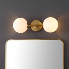 a bathroom vanity with two lights and a mirror on the wall next to it,