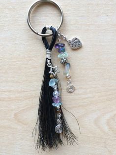 a tasseled keychain with beads and charms attached to it on a wooden surface