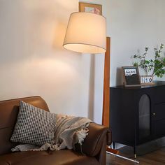 a living room with a brown leather couch and lamp