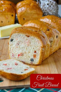 a loaf of bread sitting on top of a wooden cutting board next to some fruit