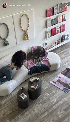 a woman laying on top of a white couch in a living room next to jewelry