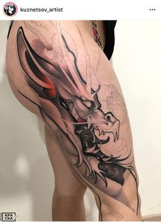 a woman's thigh with a dragon tattoo on the leg and an orange eye