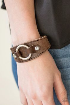 A shiny silver ring is studded in place across the front of a rustic leather band, creating a rugged centerpiece. Features an adjustable snap closure.   Sold as one individual bracelet. Luxury Brown Leather Bracelet, Elegant Style, Elegant Luxury Brown Leather Bracelet, Cheap Casual Leather Bracelet, Adjustable Rustic Jewelry With Leather Strap, Adjustable Rustic Leather Bracelet For Everyday, Rustic Adjustable Leather Bracelet For Everyday, Adjustable Rustic Bracelet In Distressed Brown, Rustic Adjustable Bracelet In Distressed Brown, Rustic Adjustable Distressed Brown Bracelet