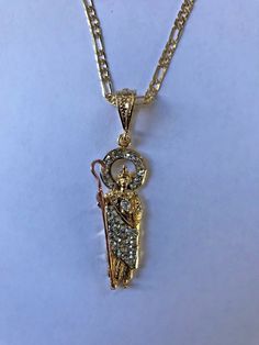 "St. Judas 14k Plated Gold and Crystal Necklace. Made in Mexico// San Judas Tadeo 14k chapeado en oro diamantado con cristales blanco transparente y cadena Hecho en Mexico Pendant measurement: 4cm //Medida del dije: 4cm Weight: 0.2 oz (7 grams) //Peso: 0.2 oz (7gramos) Necklace measurement: 24¨inches, 2mm anchor//Medida de la cadena: 24\" pulgadas, 2mm anchor Weight: 0.1 oz (5 grams) //Peso: 0.1 oz (5 gramos)" Diamond Figaro Chain Jewelry As Gift, 14k Yellow Gold Jewelry With Bling, 14k Gold Yellow Gold Jewelry With Bling, 14k Yellow Gold Bling Jewelry, Yellow Gold 14k Bling Jewelry, Spiritual Jewelry Pendant With Figaro Chain, Spiritual Pendant Jewelry With Figaro Chain, Gold Bling Pendant Necklace, 14k Gold Jewelry With Bling