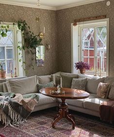 a living room filled with lots of furniture next to two windows and a rug on the floor