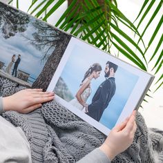 a man and woman laying on top of a blanket holding an open book with photos