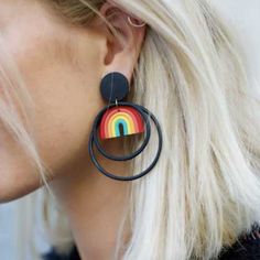 a woman with blonde hair wearing large black hoop earrings and rainbow design on the front