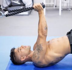 a shirtless man is doing exercises on a blue mat with a rope in his hand