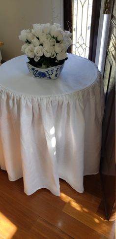 a vase with white flowers sitting on top of a table in front of a window