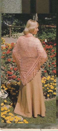 a woman standing in front of flowers wearing a shawl