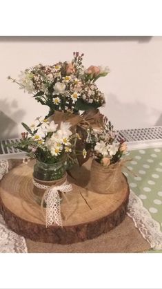 two vases filled with flowers sitting on top of a tree stump