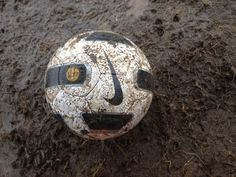 a dirty soccer ball sitting in the mud