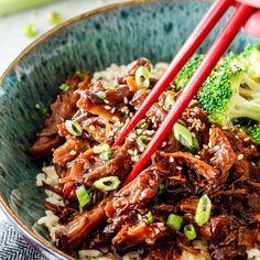 a bowl filled with beef, broccoli and rice topped with chopsticks