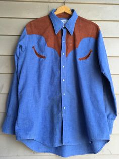 "Vintage pearl snap western shirt from the legendary Rockmount Ranch Wear. Light blue chambray with tan ultrasuede accents. Classic western welt pockets with fancy trim. Fits an estimated unisex medium/large depending on desired fit. Please use measurements provided to determine if it will fit the way you like. Very good vintage condition, a few minor spots but no other major flaws noted. Feels like a cotton/poly blend, it is lightweight and soft. Ultrasuede feels like polyester. Tags are very f Western Style Brown Tops For Ranch, Western Style Relaxed Fit Medium Wash Tops, Fitted Western Style Cotton Shirt, Brown Western Style Shirt For Fall, Brown Western Shirt For Fall, Western Style Denim Blue Cotton Shirt, Vintage Relaxed Fit Shirt For Rodeo, Western Style Denim Blue Shirt For Rodeo, Medium Wash Fitted Western Tops