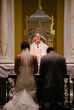 a man and woman standing in front of a priest