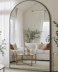 a living room filled with furniture and a large mirror on the wall over a coffee table